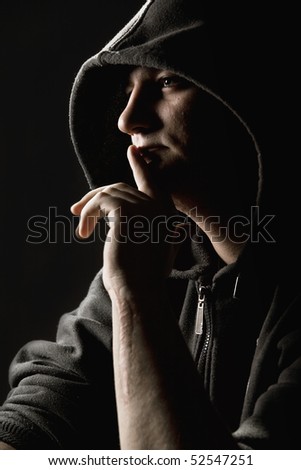 Hooded man holding a finger to his mouth