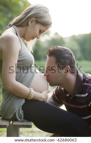 Happy pregnant woman with his husband at beautiful sunny day in park