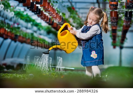 people - children, gardening and profession concept - happy children  taking care of flowers in greenhouse