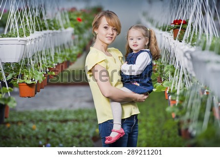 people - children, gardening and occupation concept - happy children taking care of the flowers in the greenhouse. Mom showing baby flowers and playing with your child