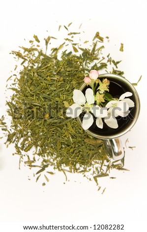 Cup of tea with flower and tea leafs, isolated on white background