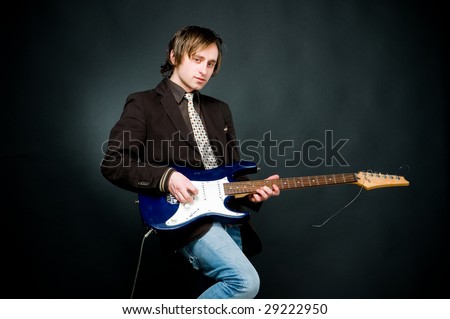 Young man playing electro guitar, studio shot