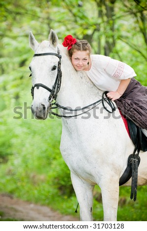 Beautiful girl riding white horse in the forest