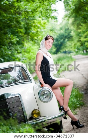 stock photo Smiling pinup styled girl sitting on retro car