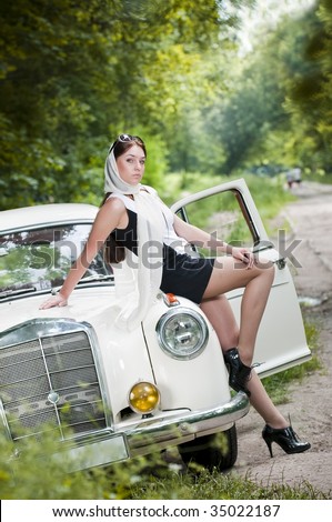 stock photo Attractive pinup styled girl sitting on retro car