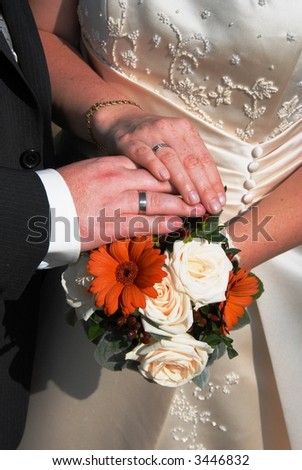 Married couple hold hands on bouquet of flowers