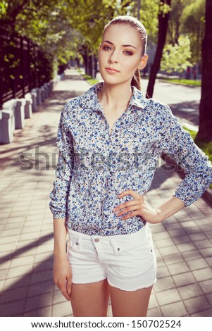Portrait of a beautiful young woman walking down the street, looking at camera, outdoors
