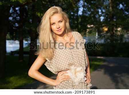 Portrait of beautiful young woman with blonde hair and blue eyes in park