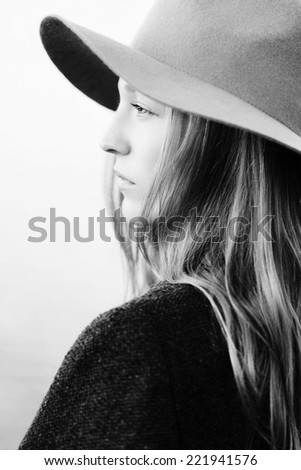 Closeup portrait of girl standing outside. Profile to camera. Wearing hat and jacket.