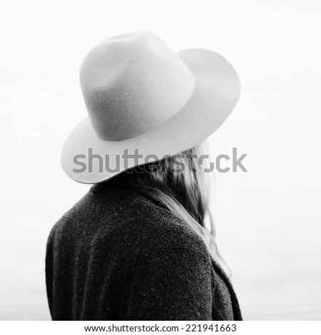 Portrait of girl standing back to camera outside. Wearing hat and jacket. Outside