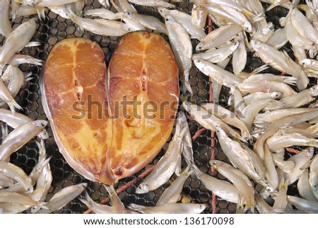 A heart shape fish and little fish dried in the sun on the net