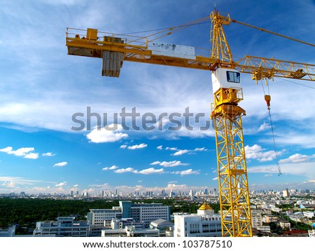 Part of yellow construction tower crane arm against blue sky