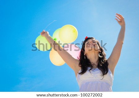 Happy woman on spring season with balloons on blue sky background. Bliss and freedom copy space.