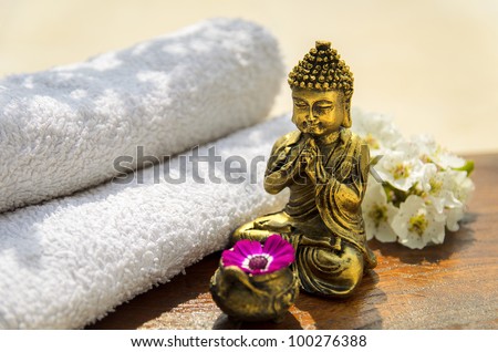 Spa concept with Buddha, towels, flowers and wood.