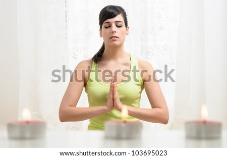 Yoga and relax exercising at home with candles. Woman meditating indoors. Beautiful caucasian model.