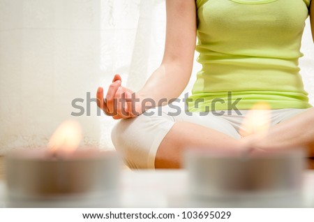 Yoga meditation at home. Relax concept with unrecognizable spiritual young woman sitting in front of candles. Caucasian concentrating model. Copyspace.