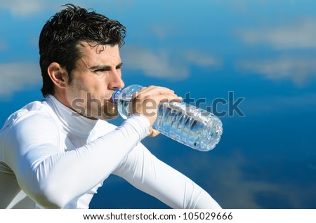 Sportsman drinking. Young male athlete drinking from water bottle after training. Copy space.