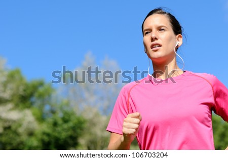 Female athlete running with earphones outside. Caucasian young model. Copy space.