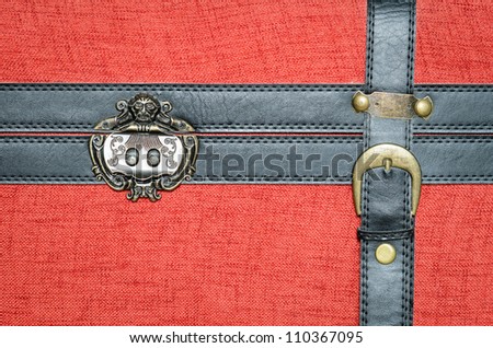 Closure of an old trunk, covered with red fabric, with black leather straps and metal buckle gold.