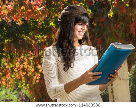 Young brunette studying and reviewing the lesson on autumn park background