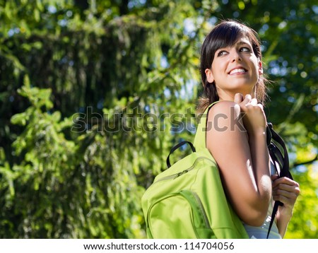 Happy girl student on summer / spring park with backpack. College girl with school bag smiling happy. Young brunette caucasian university student outdoor.