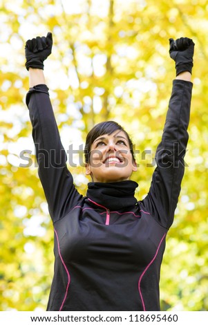 Happy sportswoman with arms up celebrating victory. Winner beautiful brunette caucasian model.