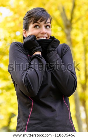 Cold autumn sport woman shivering with scarf. Caucasian brunette athlete trees on background.