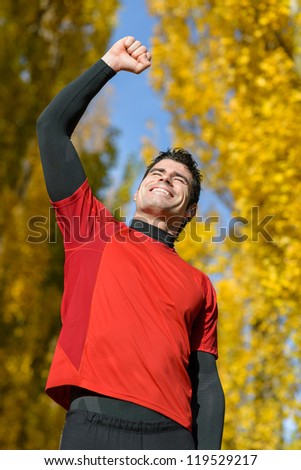 Successful sportsman winning. Male Happy athlete raising arm celebrating achievement on autumn.