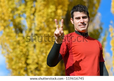 Male sport man doing  the V for victory with one hand. Winner young athlete.
