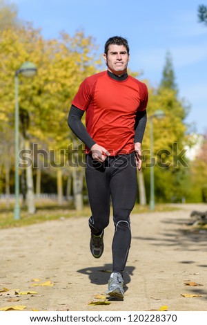Runner in park. Handsome athlete jogging outdoors on autumn.