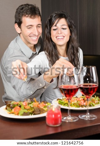 Young couple on anniversary date. Young Man and woman smiling and cooking together, preparing a romantic dinner.