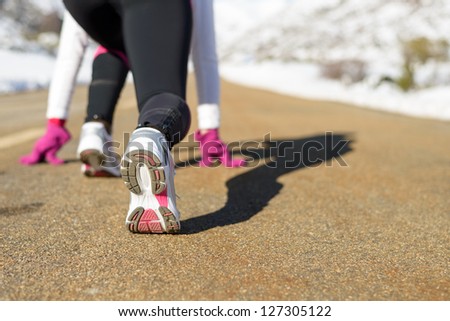 Sportswoman running on winter concept. Female athlete ready to run on mountain snowy road. Copy space.