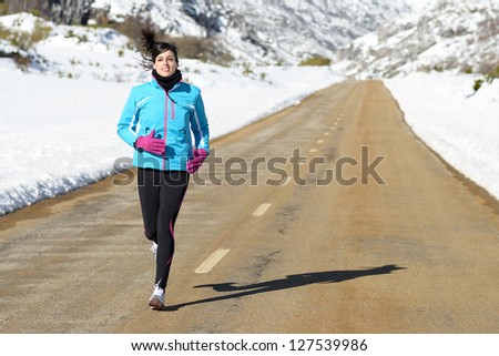 Athlete woman running on road winter snow mountain outdoors. Sport fitness woman exercising on nature.