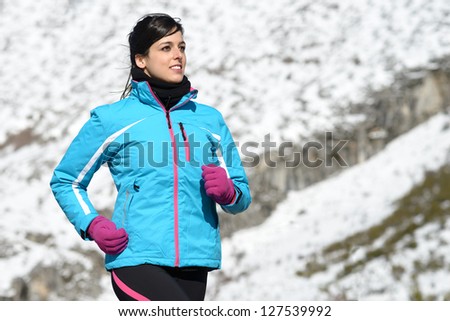 Athlete woman running on winter snow mountain outdoors. Sport fitness woman training trail on nature.