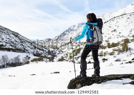 Woman hiking on winter snowy mountains. Hiker looking nature landscape on winter vacations travel.