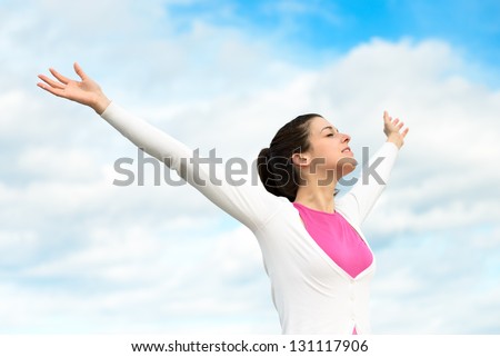 Happy woman freedom blissful concept. Woman with arms up raised to sky relaxing on spring / summer holidays outdoors. Caucasian brunette girl model.