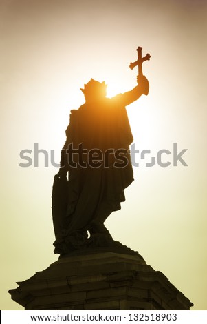 Monument to king Don Pelayo in Gijon, Asturias, Spain. Statue of warrior king holding cross after the battle. Golden sunset sun on background.