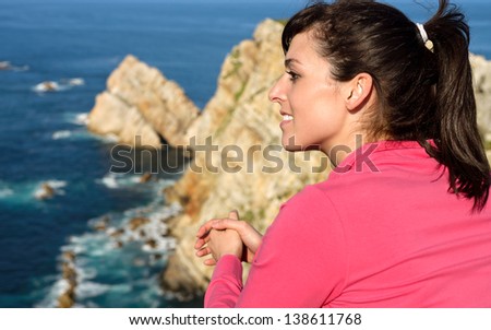 Happy woman looking at beautiful coast landscape and sea. Brunette tourist enjoying peace and relax on summer vacation travel sunny day. Cabo de PeÃ?Â±as, Asturias, Spain.
