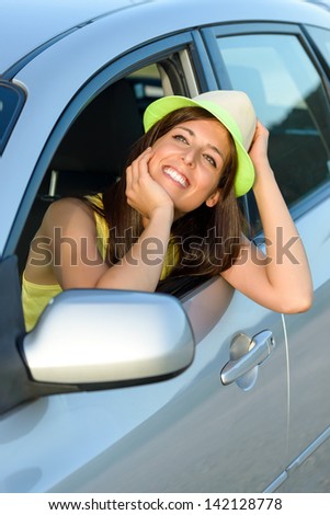 Happy woman in car looking day dreaming out of the window. Beautiful teen driver.