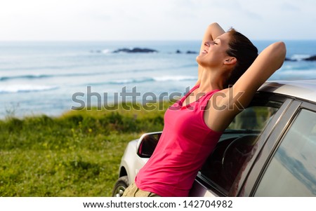 Woman Leaning On Car On Summer Travel To Coast. Happy Girl On Road Trip Enjoying Peace And Silence Relaxing On Nature.