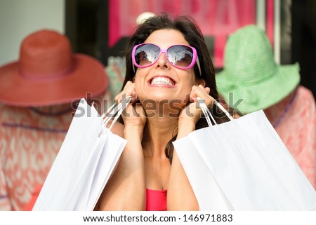 Happy woman after shopping holding white bags. Female shopper very excited and nervous after buying in the sales.