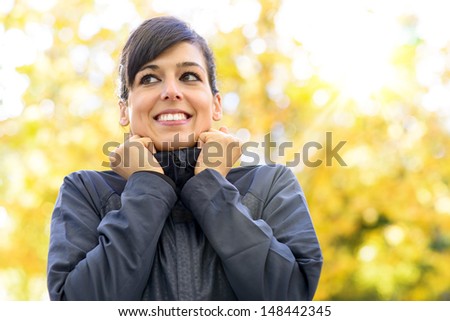 Sportswoman feeling cold on autumn sport training day. Female athlete getting ready before running or exercising outdoors. Caucasian sporty woman on fall copy space background.