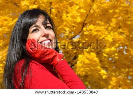 Beautiful happy woman autumn portrait. Dreamy cheerful woman on golden yellow autumnal foliage copy space background.