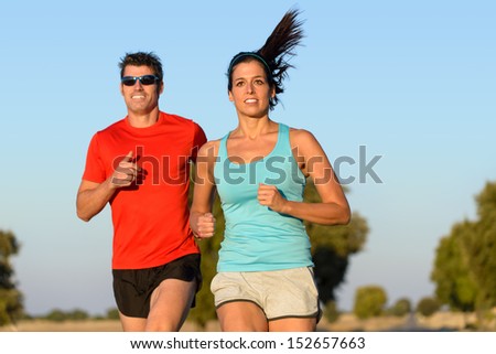 Fitness couple running in country road. Cheerful runners training outdoors on summer for sport and healthy lifestyle.