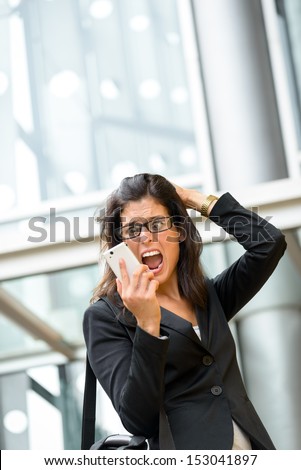Upset businesswoman screaming crazy on phone. Anxious woman on business problems and crisis receiving bad financial news on smartphone. Hispanic executive suffering stress, panic and anxiety attack.