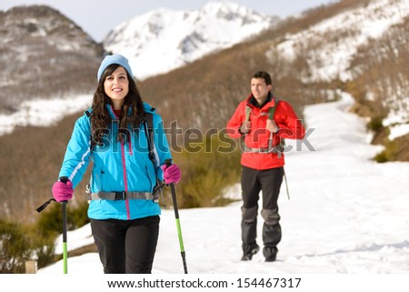 Couple hiking in winter on snowy mountain. Man and woman walking and exploring nature on adventure travel.