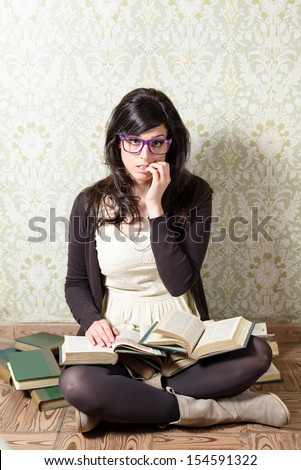 Tired and nervous girl studying for exams and biting her nails. Upset woman sitting on the floor with lots of old books.