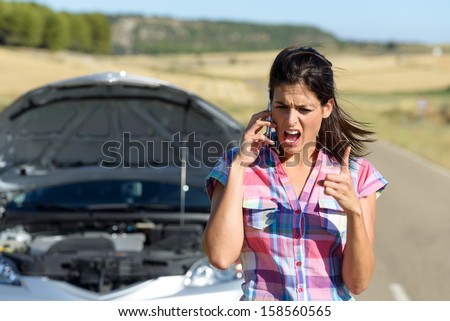 Angry and desperate woman calling to insurance assistance service after car accident. Upset woman on cellphone discussion explaining broken down auto engine.
