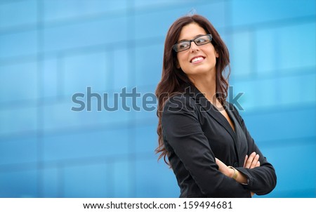 Businesswoman in leadership confident pose outside corporate building. Business woman crossing arms and smiling.