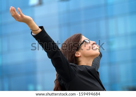 Successful businesswoman raising arms outdoor. Business woman celebrating freedom and success.